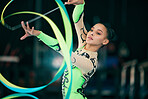 Sports, gymnastics and female performing with a ribbon for a competition or training in sport arena. Fitness, athlete and woman practicing for balance, endurance and flexibility exercise for routine.