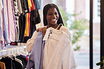 Clothes, retail and portrait of black woman shopping in a boutique, happy and smile while feeling fabric. Face, fashion and girl customer excited for clothing sale, discount or outfit choice in store