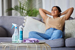 Cleaning product, woman and sofa to relax, rest or sleep for domestic work in living room with relief. Happy cleaner, lounge couch with spray, cloth and bottle on table for service, job and hygiene