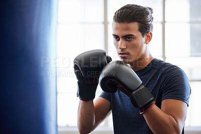 Buy stock photo Man, boxing and fitness in gym exercise for power, performance and cardio against a window background. Boxer, fighter and athletic male training on punching bag at sports center, serious and tough