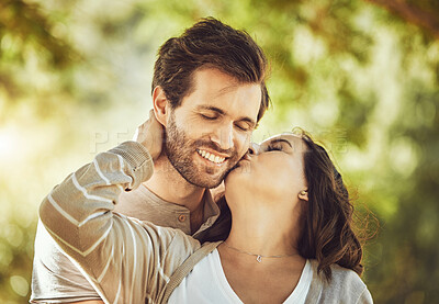 Buy stock photo Kiss, love and couple at park, smile and having fun time together outdoors. Valentines day, romance and care, affection and intimacy of happy man and woman kissing cheek on romantic date outside.