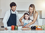 Learning, parents or child cooking vegetables as as happy family in a house kitchen with organic food for dinner. Development, father or mom teaching, helping or cutting tomato with a healthy girl