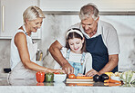 Learning, grandparents or girl cooking as a happy family in a house kitchen with organic vegetables for dinner. Grandmother, old man and child helping or cutting carrots for a healthy vegan food diet