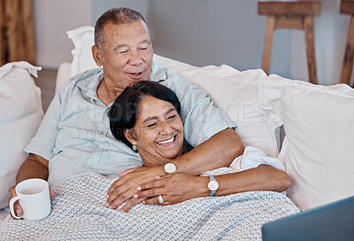 Buy stock photo Senior couple watching a movie on a sofa with a laptop while relaxing in their living room. Love, coffee and happy elderly man and woman in retirement streaming a video on computer together on couch.