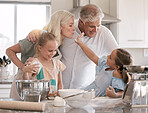 Happy family, baking and children helping grandparents in home kitchen with food. Woman, man and girl kids learning to make cookies, pancakes or cake for breakfast with love, care and teamwork