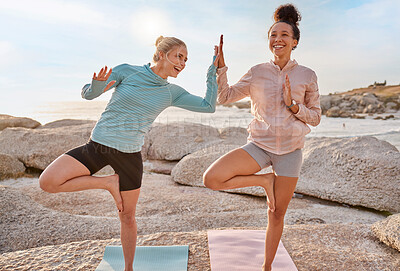 Buy stock photo Women friends, beach yoga and happy in morning with stretching pose for health, wellness and helping hand. Black woman, fitness group and laugh for comic moment with balance, peace and support by sea