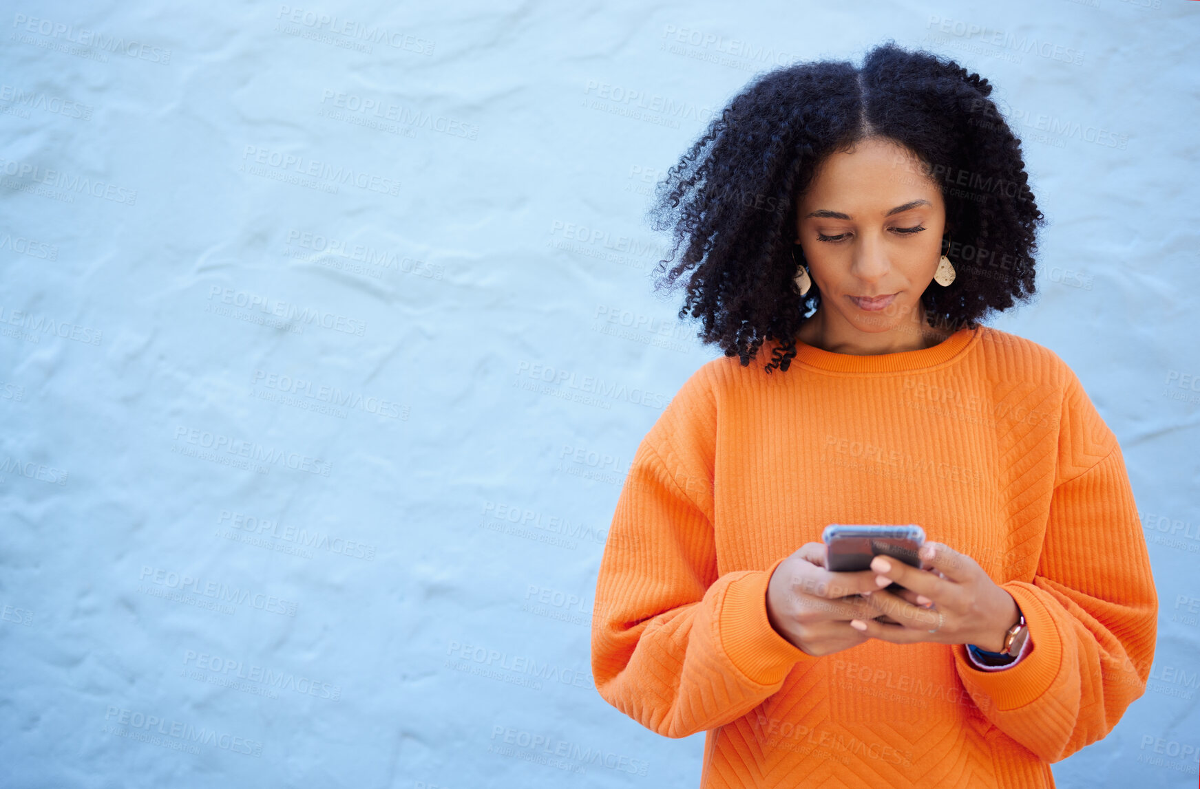 Buy stock photo Black woman, cellphone and typing on blue background, wall or mockup. Female with mobile, technology and social media for reading notification, online advertising and website contact on 5g networking