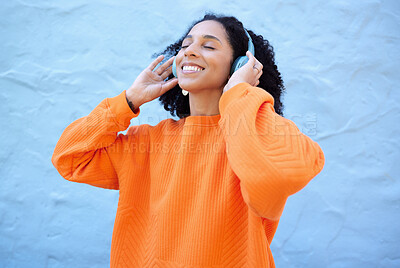 Buy stock photo Black woman, headphones and music with smile by wall background on urban adventure, relax and freedom. African gen z girl, streaming audio and quality sound on app, web or internet with peace in city