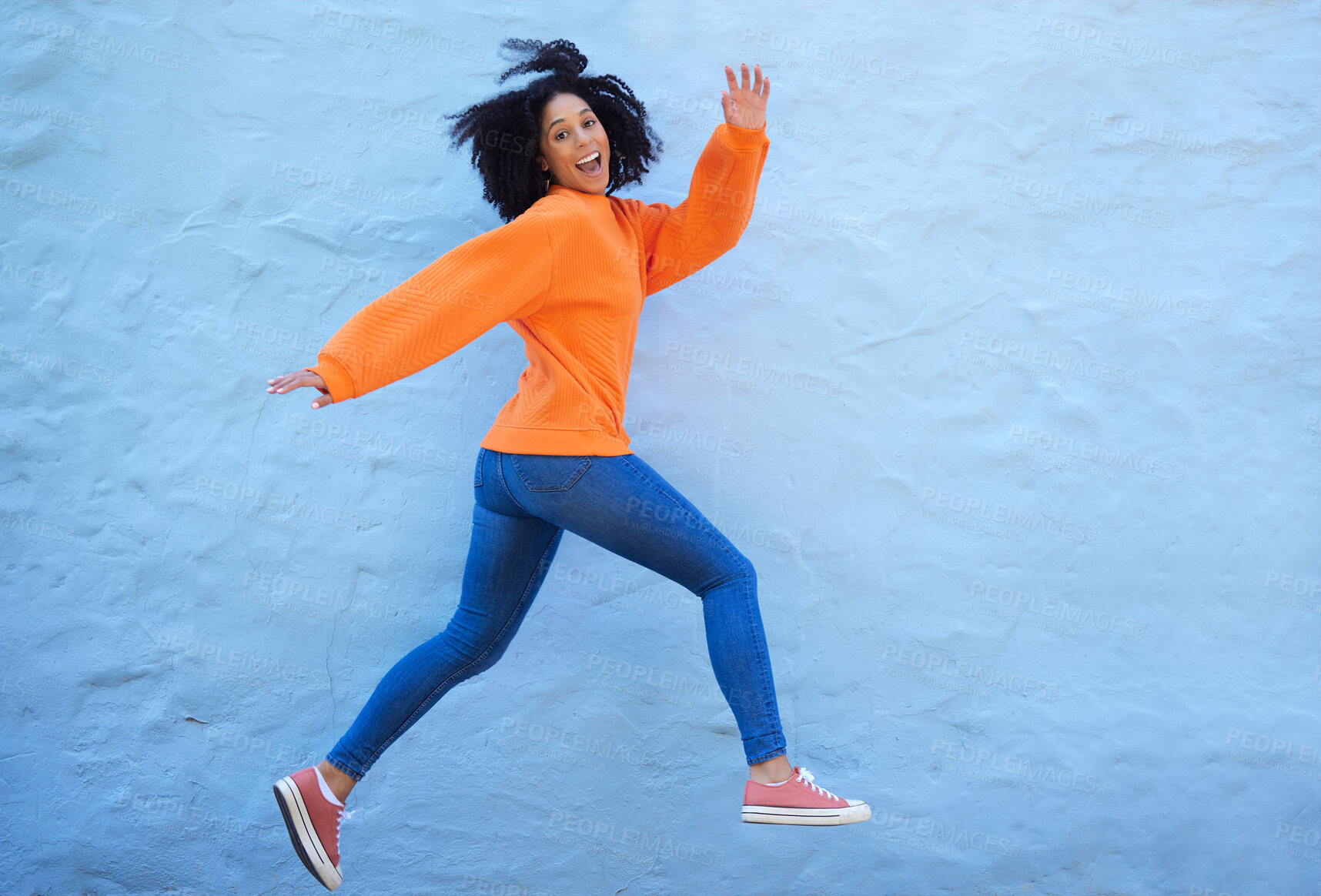 Buy stock photo Happy, excited and woman jumping by a wall while walking in the city on a vacation or weekend trip. Happiness, smile and young lady from Mexico with energy, freedom or adventure in town on a holiday.