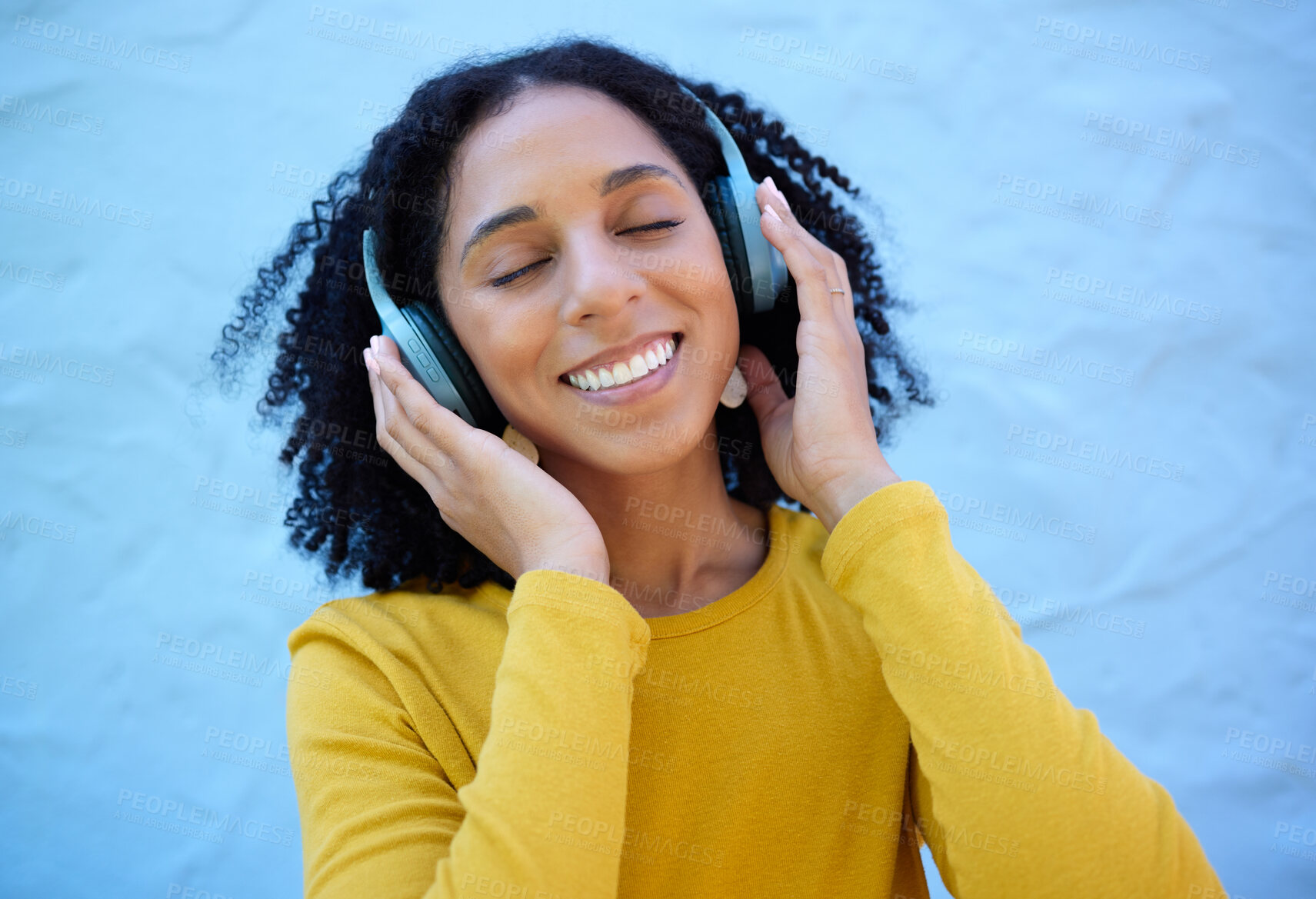 Buy stock photo Black woman, music headphones and smile on wall background, blue backdrop or outdoor. Happy girl listening to radio, podcast and sound of streaming, audio or face of happiness, relax or hearing tech