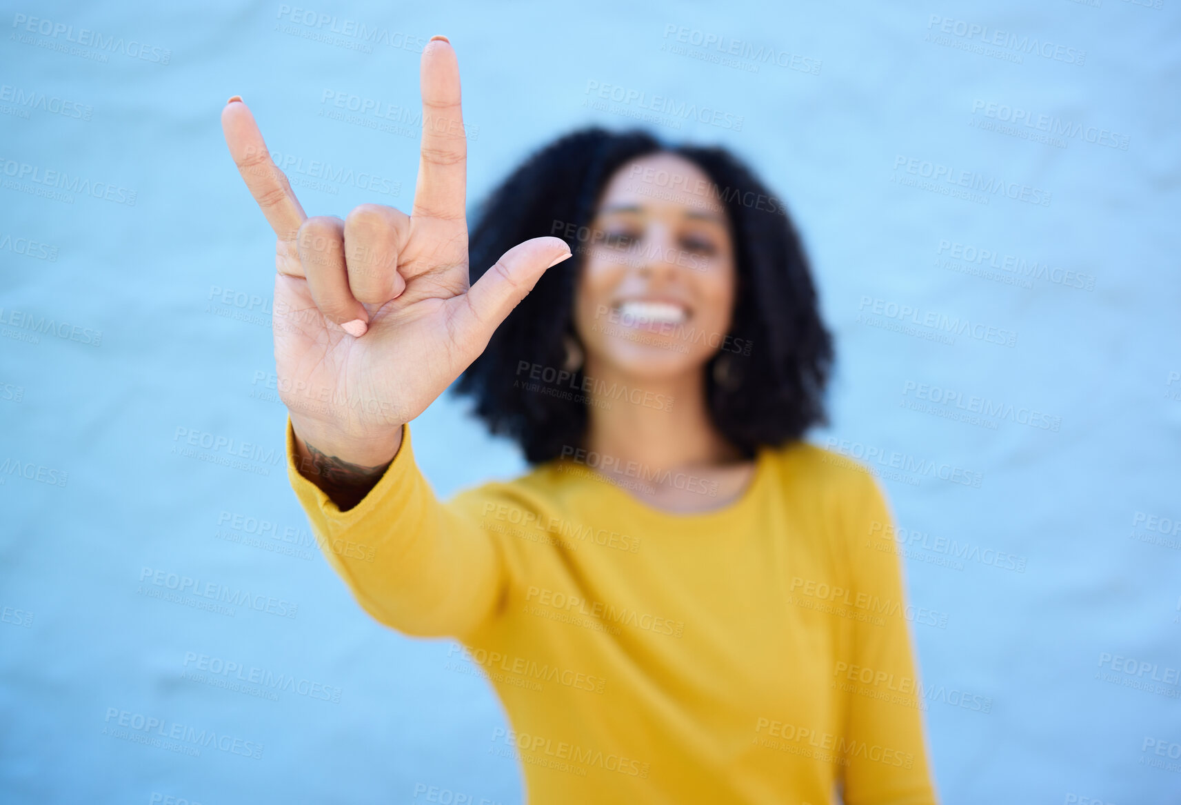 Buy stock photo Rock sign, fashion and hands of black woman on blue background with smile, happy mindset and peace. Hand gesture, beauty and face of African girl relax with urban style, trendy and stylish clothes