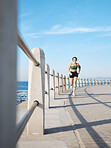 Fitness, woman and running by the beach side for exercise, training or cardio workout in Cape Town. Active female runner enjoying summer run or exercising for healthy wellness in the nature outdoors