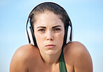 Headphones, fitness and portrait of woman in focus, mindset and goals of podcast or music for motivation. Challenge, power and athlete or sports person face listening to audio technology on blue sky