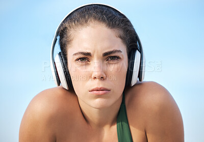 Buy stock photo Headphones, fitness and portrait of woman in focus, mindset and goals of podcast or music for motivation. Challenge, power and athlete or sports person face listening to audio technology on blue sky