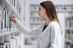 Woman in library, education and student with book search, choice and option with reading and learning at university. Knowledge, story and fiction with textbook, study and browsing bookshelf on campus