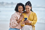 Phone, beach and internet with black woman friends outdoor together by the ocean or sea in the morning. Nature, mobile or social media with a young female and friend reading a text on the coast