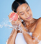 Black woman, water splash or skincare grapefruit on blue background in facial hydration, healthcare or isolated wellness. Beauty model, happy or wet with citrus food for vitamin c or face dermatology