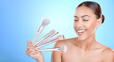Buy stock photo Woman, brushes and smile for makeup, cosmetics or beauty against a blue studio background. Female gen z model smiling for cosmetic skincare, facial glow aesthetic or foundation product on mockup