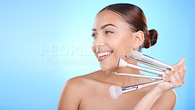 Buy stock photo Black woman, studio and smile with makeup brushes in hand for face beauty, cosmetics and happy by blue background. Gen z model, cosmetic skincare and facial glow aesthetic for foundation product