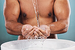 Closeup, basin and man washing hands, water splash and hygiene on blue studio background. Zoom, male and gentleman in bathroom, cleaning and morning routine for grooming, skincare and smooth skin