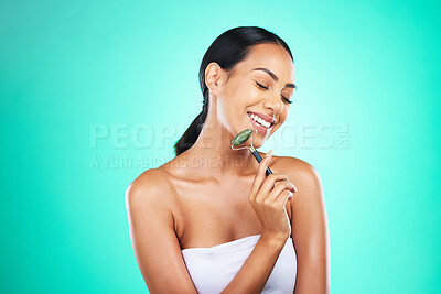 Buy stock photo Beauty, jade roller and woman with face massage in studio for wellness, grooming or skincare on blue background. Happy, facial and massaging tool by girl model relax, skin or product while isolated