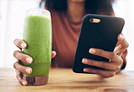 Hands, smoothie and phone with a black woman in the kitchen of her home for health, weight loss or nutrition. Mobile, glass and wellness with a female posting a status update on social media