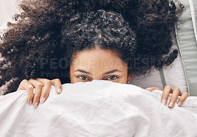 Buy stock photo Above bed, portrait and black woman in the morning after sleep rest and relaxing at home with blanket. Eyes, house and wake up happiness of a young person hiding face under the bedroom covers 