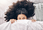 Bed, wink portrait and black woman in the morning after sleep and  rest at home with blanket. Eyes, house and wake up happiness of a young person hiding face under the bedroom covers on a pillow