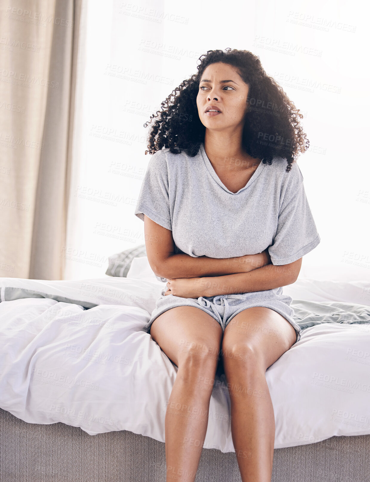 Buy stock photo Black woman, sick and stomach ache on house bed, home or bedroom in period pain, menstruation cramps or ibs crisis. Hurt person, injury and abdomen tummy in healthcare emergency or appendicitis risk