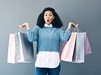 Wow, sale and portrait of woman with shopping bags, retail therapy and surprise at gift on a wall. Deal, excited and happy girl holding products from a shop, market or mall on a grey background