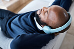 Music top view, headphones and black man on sofa in home living room streaming audio. Meditation, relax technology and male on couch in lounge listening to peaceful podcast, radio or sound in house.