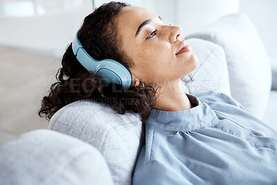 Buy stock photo Black woman, headphones and relax on sofa with music, audio streaming and peace with smile in lounge. Young lady, sound technology and listening to radio, podcast and thinking on living room couch