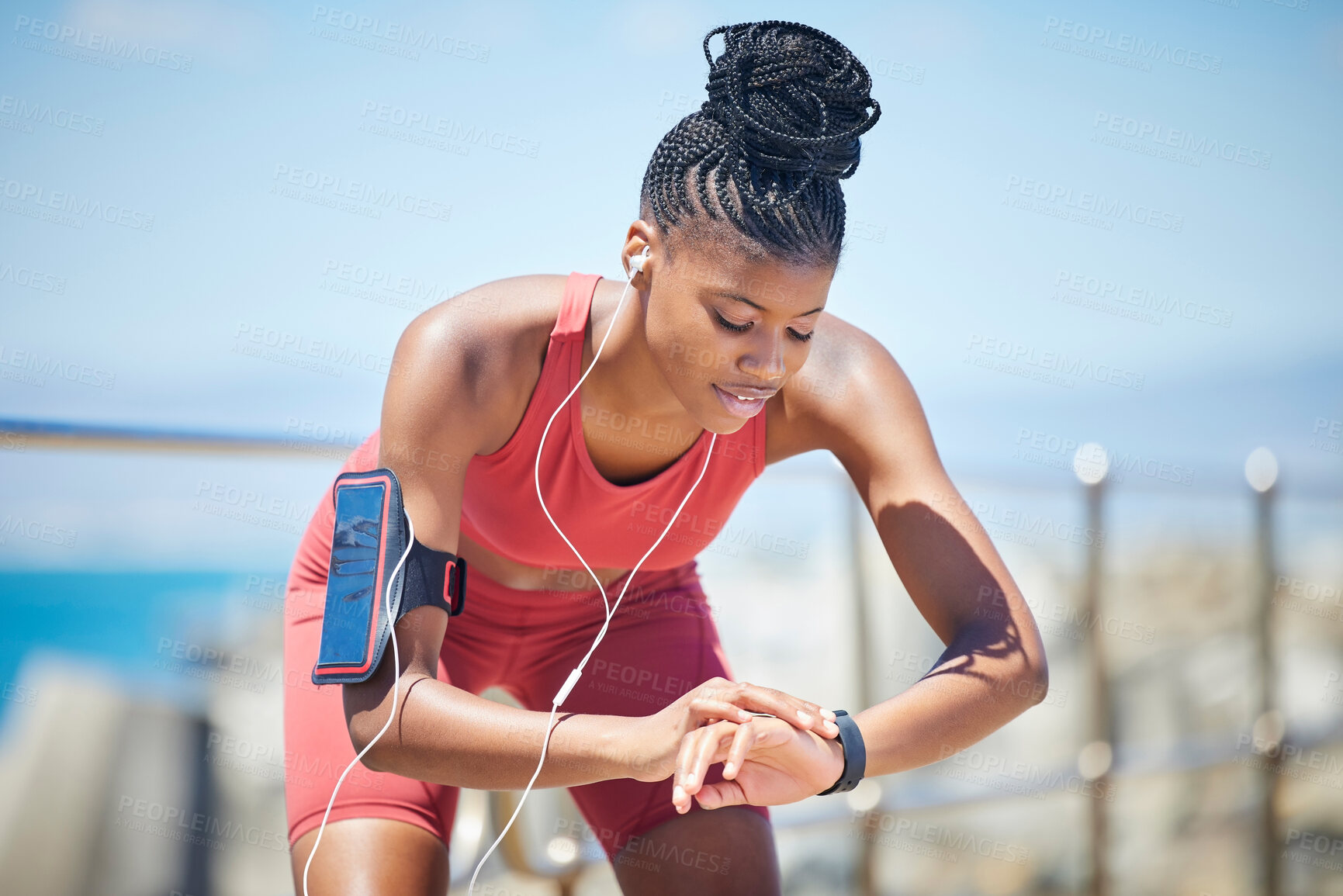 Buy stock photo Fitness, smartwatch and runner time of a black woman by the sea doing exercise and running workout. Outdoor, run tracker app and mobile of a athlete with headphones by the ocean listening to audio