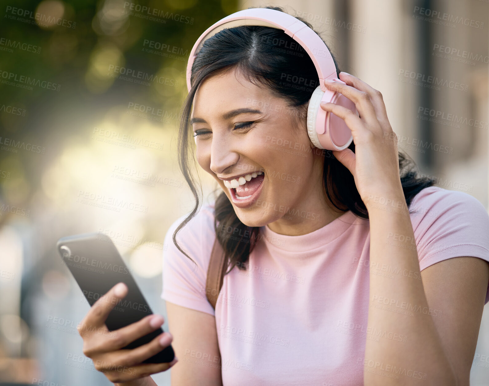 Buy stock photo Headphones, music or video call by laughing woman in a city for travel, happy and joke on building background. Radio, podcast and funny meme for girl student with app, online audio or a positive post