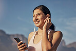 Woman, fitness and phone for music in nature outdoor for exercise, training and workout. Happy model person listening to earphones for podcast, audio and motivation for health and wellness blue sky