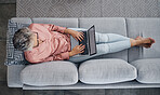 Senior woman, laptop and sofa above relaxed in the living room checking email, typing or writing at home. Elderly female freelancer or writer relaxing on lounge couch working or reading on computer