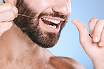 Dental, floss and oral hygiene with a man in studio on a blue background cleaning his teeth for healthy gums. Dentist, healthcare and mouth with a young male flossing to remove plague or gingivitis