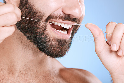 Buy stock photo Dental, floss and oral hygiene with a man in studio on a blue background cleaning his teeth for healthy gums. Dentist, healthcare and mouth with a young male flossing to remove plague or gingivitis