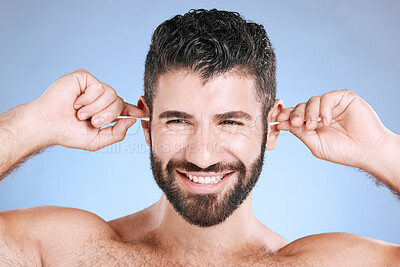 Buy stock photo Cleaning, ear and man with cotton bud in studio for hygiene, grooming and beauty routine on blue background. Earwax, product and guy model in cosmetic, luxury and wax, removal or stick while isolated