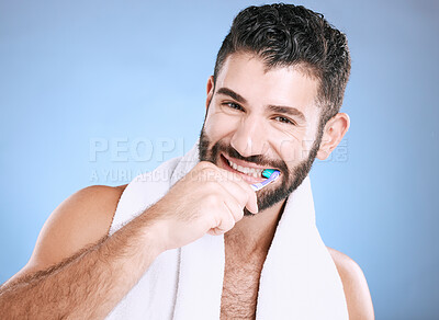 Buy stock photo Toothbrush, portrait and man brushing teeth in studio for dental wellness, healthy smile and mouth. Happy male model, oral care and fresh breath for gums, dentistry and hygiene on blue background 