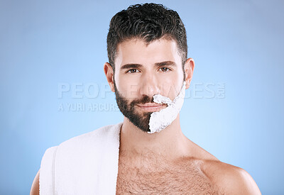 Buy stock photo Portrait of man with foam on half beard, with towel and skin product placement in studio mock up. Shaving cream on face, hair and skincare for happy male model grooming, isolated on blue background.