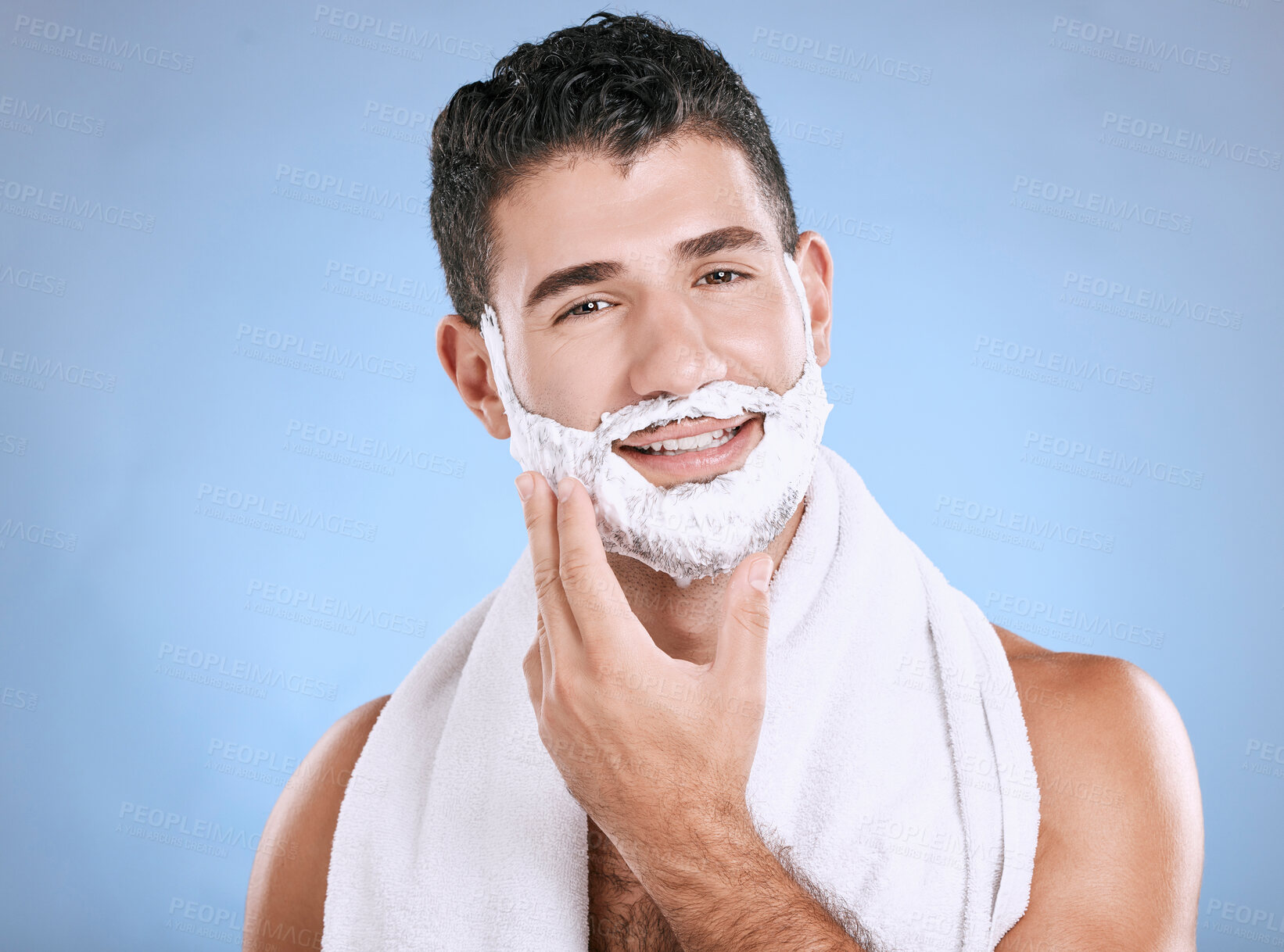 Buy stock photo Shaving foam on beard, smile and hand on face with towel and product placement in studio mock up. Shave cream, facial and hair or skincare for happy male model grooming, isolated on blue background.
