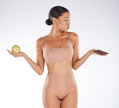 Buy stock photo Black woman, studio and choice for chocolate, apple and health for weight loss, body or nutrition by background. Gen z model, underwear or decision for diet, fruit or candy for thinking of cheat day