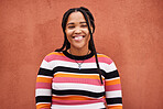 Portrait, fashion and braids with a black woman on an orange background outdoor for style or empowerment. Style, wellness and profile picture with an african american person posing against a wall