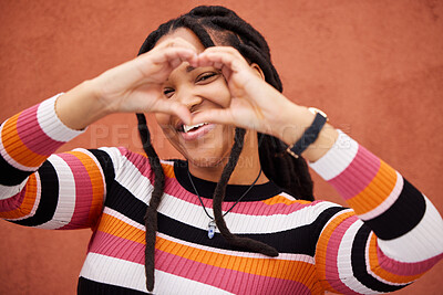 Buy stock photo Happy, heart shape and black woman by a wall in the city while on a walk on a weekend trip. Happiness, portrait and African female with a love emoji or hand gesture in town on holiday or vacation.
