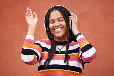 Buy stock photo Black woman, music headphones and wall with smile in city for walk, adventure and listening to edm on radio. Young gen z girl, streaming hip hop or techno on website, internet and happiness in metro