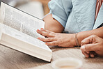 Hands, bible and reading with a senior couple studying a book together in their home during retirement. Jesus, faith or belief with a man and woman praying to god in their house for spiritual bonding