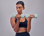 Woman, focus and dumbbell training in studio for strong body, action or thinking of mindset goals. Indian female, bodybuilder and weights of fitness, power exercise or muscle energy of sports workout