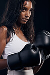 Boxing, gloves and mindset with a sports woman getting ready in studio on a black background for fitness. Exercise, health and training with a female athlete or boxer sweating during a combat workout