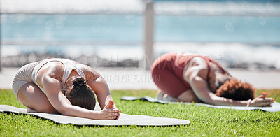 Buy stock photo Woman, yoga friends and stretching on grass for wellness, strong legs and body in morning sunshine by sea. Women teamwork, fitness and workout by ocean with support, focus and mindfulness in summer